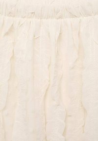 Weißer Stoff mit einem gerafften Design, variierenden Texturen, weichem Material und einem gerafften oberen Rand.