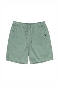 Short en velours côtelé vert clair avec taille élastique, cordon, poches latérales et une petite étiquette noire sur la poche droite.