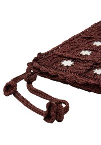 Brązowa torebka szydełkowa z okrągłymi metalowymi akcentami, szczegółową teksturą i dekoracyjnymi wiązaniami w rogach do zapięcia.