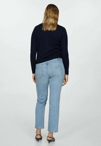 Lichtblauwe rechte jeans met een middelhoge taille, voorzien van achterzakken en een subtiele vervaagde wassing, gecombineerd met een nauwsluitend donker topje.