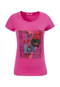 Camiseta de manga corta rosa con un estampado gráfico de una mano sosteniendo un bolso azul adornado con gemas y flores. Cuello redondo, ajuste slim.