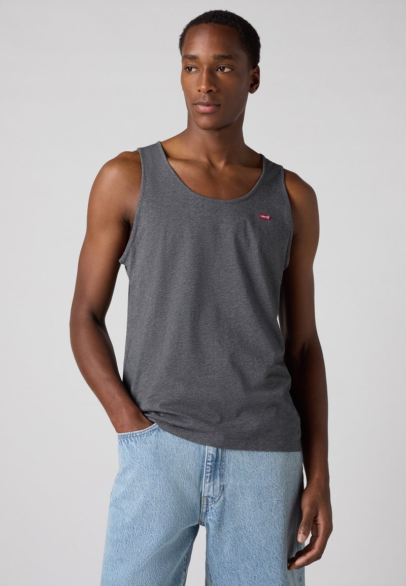 Débardeur gris en coton, avec un col rond et un petit logo Levi's rouge. Assorti à un jean en denim bleu clair.