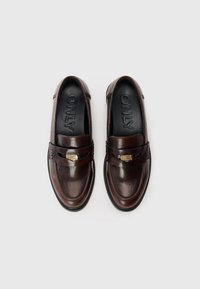 Et par mørkebrune læder loafers med detaljer af guldfarvet spænde, sorte indersåler mærket "ONLY," vist ovenfra på en hvid baggrund.
