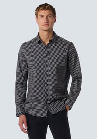 Navy langarmshirt met een geometrisch patroon in crème en roest. De stof is glad, met een puntkraag en knoopsluiting aan de voorkant.