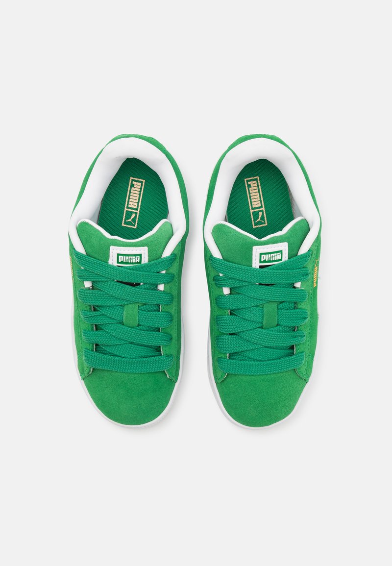 Baskets en suède vert avec des accents blancs, dotées de lacets plats, de cols rembourrés et d'un logo en relief sur la languette et sur le côté.
