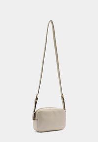 Beige læder crossbody taske med en glat overflade, rektangulær form og justerbar rem, der har hardware i gyldent tone og nitter.