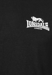 Sort bomulds T-shirt med et hvidt trykt logo af "LONSDALE" med en løvegrafik og teksten "LONDON", glat tekstur.