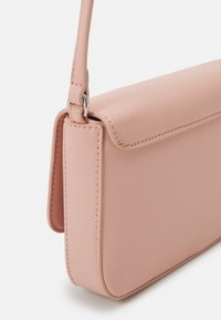 Borsa a tracolla rosa chiaro con superficie liscia e texture, forma rettangolare e chiusura a patta semplice. Presenta una tracolla sottile e dettagli di cucitura.