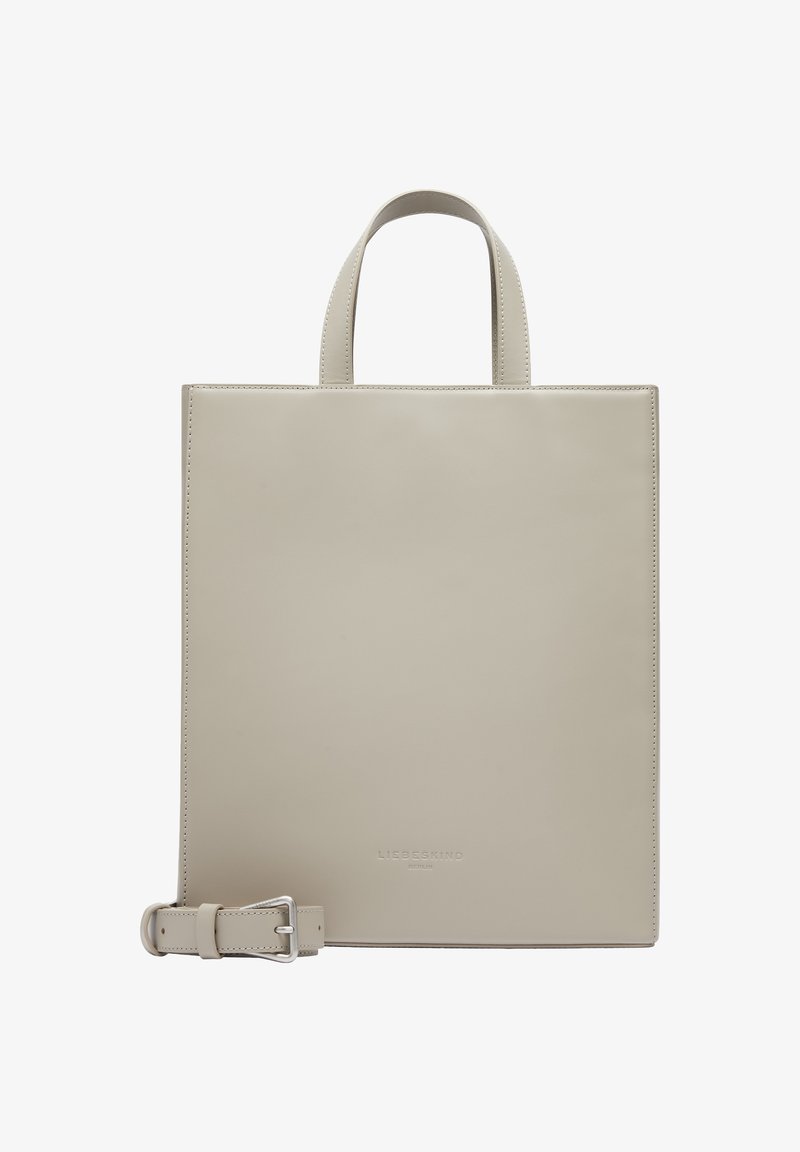 Sac fourre-tout en cuir beige de forme carrée avec deux courtes poignées, une bandoulière ajustable et un logo embossé en bas. Texture lisse, design minimaliste.