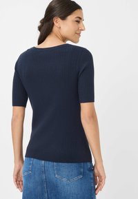 Maglione a coste nella tonalità navy con maniche corte, design aderente, scollatura ampia, tessuto testurizzato e vestibilità leggermente sagomata in vita.