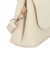 Beige Lederhandtasche mit strukturiertem Finish, ausgestattet mit einem goldfarbenen Verschluss und subtiler Markenkennzeichnung an der Seite. Rechteckige Form.