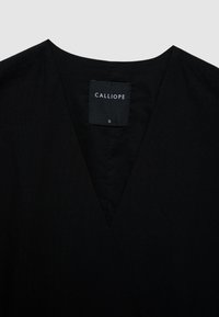 Black V-neck garment with a fabric label showing the brand name "Calliope" and size "S" on the inside collar.
