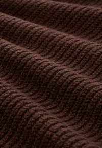 Bruine gebreide stof met een getextureerd, geribbeld patroon, die zachte, dikke vezels toont in golvende plooien.