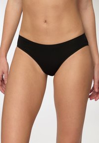 Mutande bikini in cotone nero con una texture liscia, taglio basso e dettagli di cucitura minimi, progettate per comfort e vestibilità.