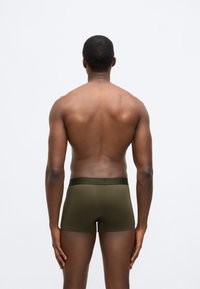 Ελιά πράσινα μποξεράκια κατασκευασμένα από μαλακό, ελαστικό ύφασμα, με λείο ελαστικό στη μέση. Η όψη από πίσω δείχνει εφαρμοστό σχέδιο.