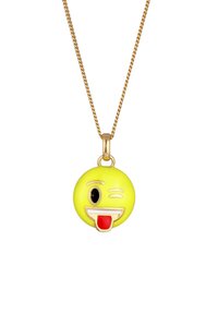 Pendentif en émail jaune en forme d'emoji avec une expression ludique, présentant des accents noirs et rouges, suspendu à une chaîne dorée.