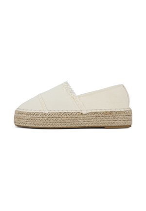 Espadrilles en toile beige avec des bords effilochés, des panneaux latéraux élastiques et des semelles en jute tressé. Design plat avec un bout fermé et un style à enfiler.
