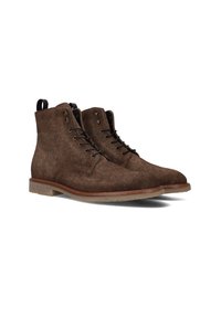 Bruine suède enkellaarsjes met ronde neus, contrasterende lichtbruine zool en zwarte veters. Voorzien van een trekband aan de achterkant voor gemakkelijke aan- en uittrekken.