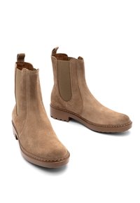 Botines de ante en marrón claro, con paneles laterales elásticos, suelas de goma planas y detalle de costura en contraste. Textura suave, diseño sencillo.