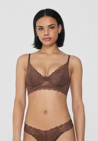 Sujetador de encaje marrón con aro y bordes festoneados. Tanga de encaje a juego con un patrón floral. Textura suave, tirantes ajustables.