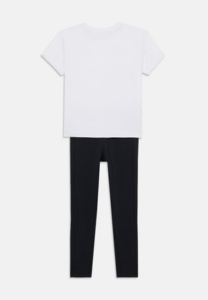 Weißes Kurzarm-T-Shirt kombiniert mit schwarzen Leggings. Das T-Shirt hat einen runden Ausschnitt; die Leggings sind eng anliegend und elastisch.