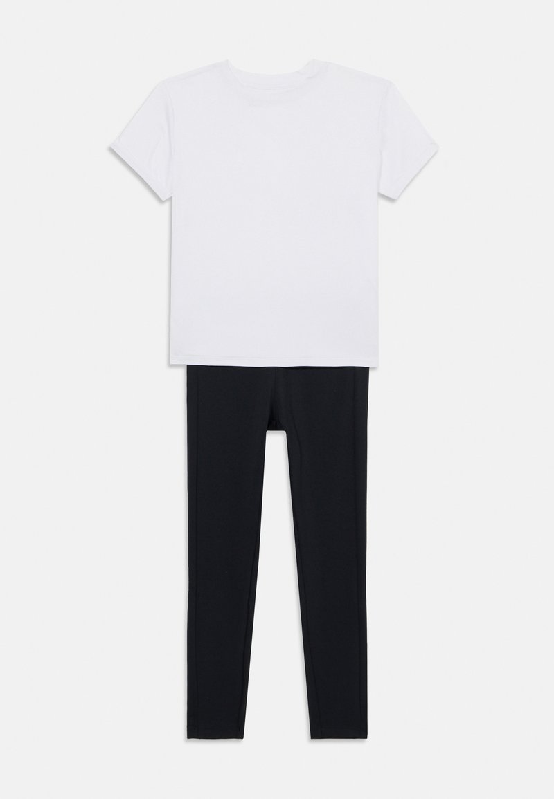 Bela majica s kratkimi rokavi je kombinirana z črnimi leginami. Majica ima okroglo izrezano ovratnik; legini so oprijetega kroja in elastični.