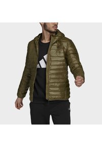 Veste en duvet verte olive avec capuche, en matériau résistant à l'eau, fermeture éclair, et motif matelassé horizontal. Logo noir sur la poitrine.