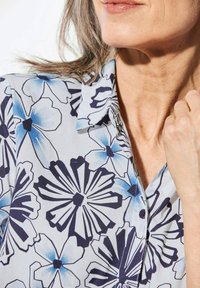 Kurzärmlige Bluse aus leichtem Stoff mit floralen Druck in Blau und Marineblau, mit spitzem Kragen und Knöpfen.