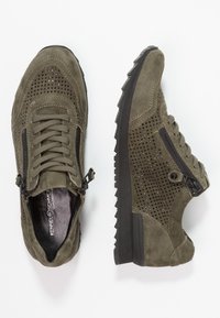Sneakers scamosciati verde oliva con design perforato, dotati di dettagli in zip nera e suole testurizzate per una migliore aderenza.