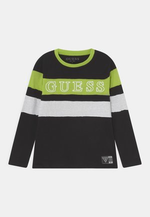 Black long-sleeve shirt with green and white horizontal stripes, "GUESS" printed across chest, and brand patch near hem.