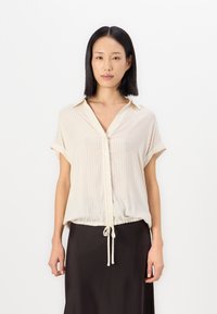 Light beige short-sleeve blouse with vertical stripes, a collar, and a drawstring hem. White buttons down the front add detail.
