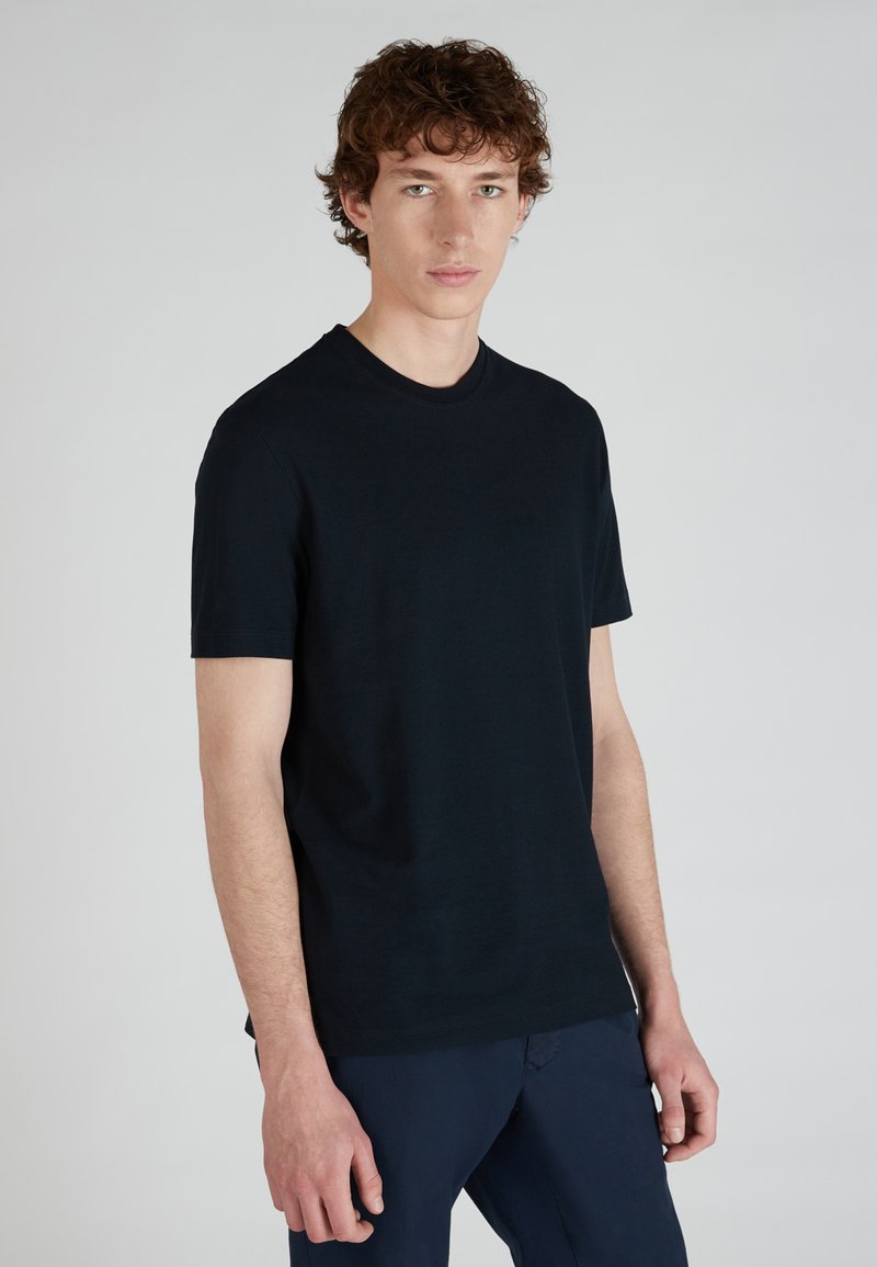 T-shirt bleu marine à manches courtes en tissu doux avec un col ras du cou. Le design est simple, sans logos ni motifs visibles.