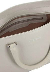Bolso tote de cuero texturizado beige con dos asas, un compartimento con cremallera y un logo grabado en el interior.