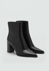 Črni usnjeni gležnjarji s koničastim nosom in kvadratnim peto. Gladka tekstura, minimalističen dizajn in stranski zadrga.
