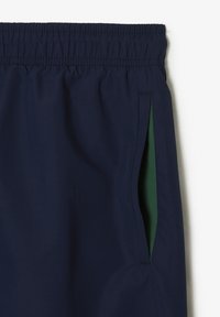 Marineblaue, leichte Shorts mit elastischem Bund und seitlichen Taschen, die grün gefüttert sind. Der Stoff wirkt glatt und strapazierfähig.