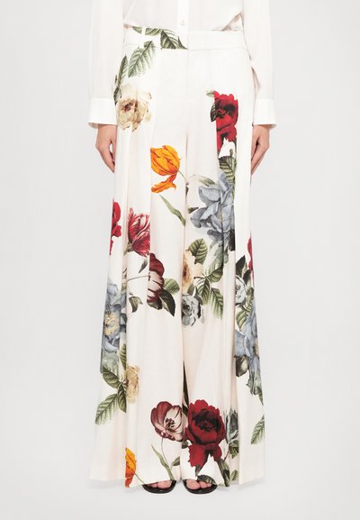 Pantalons larges fleuris en tissu léger, avec un fond crème et des fleurs colorées en rouge, bleu, jaune, et des feuilles vertes.