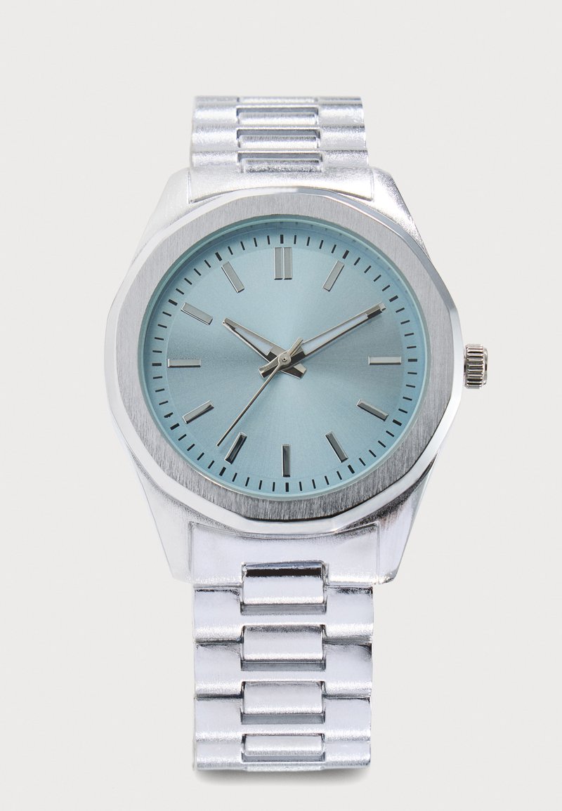 Montre-bracelet en métal argenté avec cadran bleu, index heures argentés et aiguilles indiquant 10:10:36.