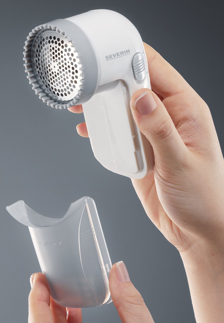 Weißer Stoffrasierer mit einem runden Netzaufsatz, ergonomischem Griff und einer durchsichtigen Abdeckung, die in einer Hand gehalten wird. Einfaches Design zur Fusselentfernung.