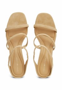 Sandalias de ante beige con punta cuadrada, tres correas entrelazadas y una plantilla acolchada. Presenta un logo grabado en la plantilla.
