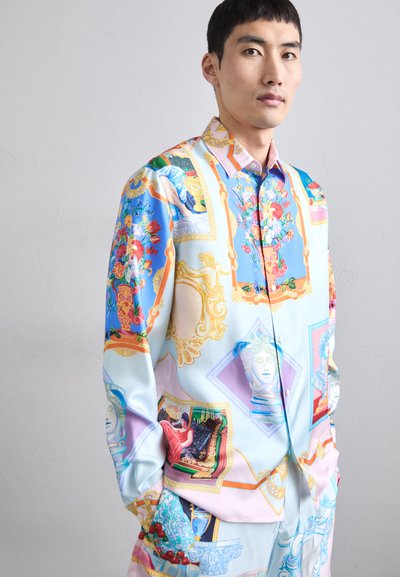 Camicia oversized in tessuto seta di colore azzurro pastello, decorata con motivi floreali ornati e opere d'arte classiche. Presenta una chiusura con bottoni e maniche lunghe.