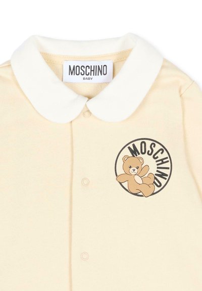 Maglietta per neonati color crema con colletto bianco arrotondato, bottoni a pressione e logo orsetto con scritta "MOSCHINO" sul petto.