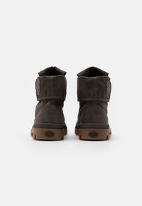 Botas de tobillo gris oscuro con un cuello doblado, tejido texturizado, acento de logo circular y suelas de goma marrón con un agarre con patrón.