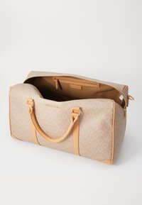 Μπεζ τσάντα duffle με γεωμετρικό μοτίβο, ταμπά δερμάτινες λεπτομέρειες, διπλούς ιμάντες και ευρύχωρο εσωτερικό με διαμέρισμα που έχει φερμουάρ.