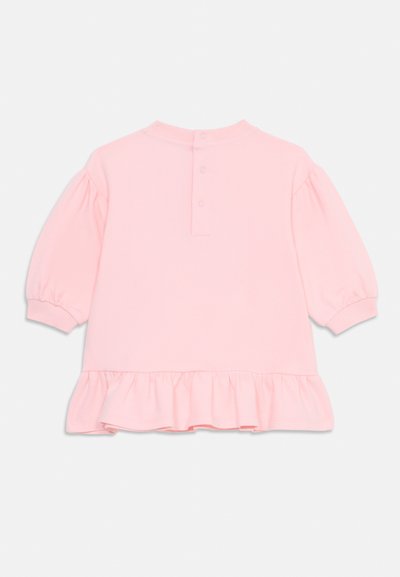 Rosa tröja med puffärmar, rund halsringning och volangkant. Har knappstängning baktill. Tillverkad av mjukt, texturerat tyg.
