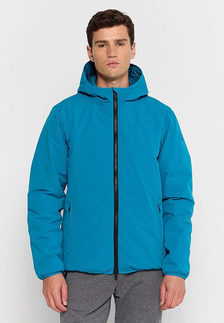 Giacca isolante color turchese con zip frontale, cappuccio e polsini elasticizzati. Presenta tasche laterali e una texture del tessuto liscia e resistente all'acqua.
