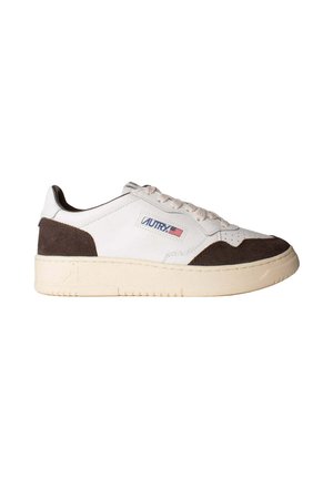 Zapatilla blanca de perfil bajo con detalles en ante marrón, suela crema, cordones y una etiqueta con el logo y la bandera americana en el lateral.