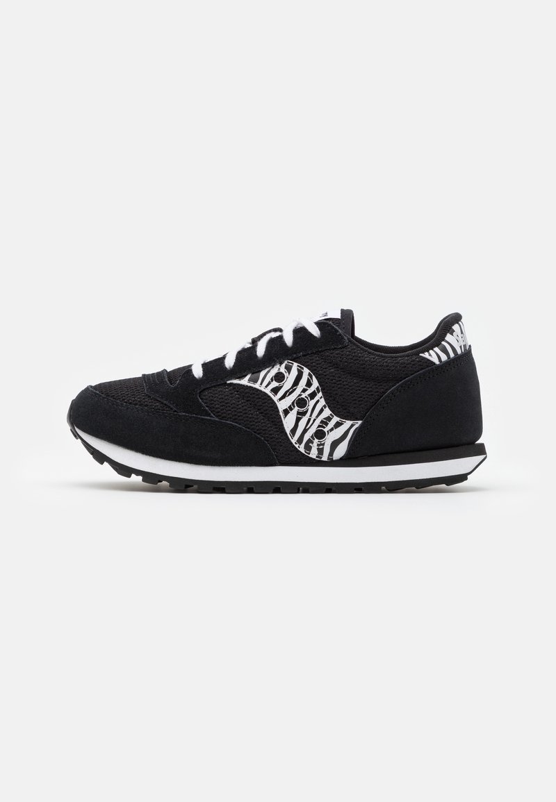 Baskets de sport noires avec lacets blancs et logo à motif zèbre sur le côté, vues de l’intérieur sur fond blanc.