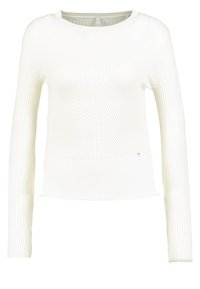 Weißes Langarm-Strickoberteil mit geripptem Design, das eine figurbetonte Silhouette und einen runden Halsausschnitt aufweist. Dezentes Logo-Detail nahe dem Saum.
