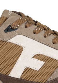 Bruna mocka- och mesh-sneakers med vita accenter, strukturerat tyg, vadderad tunga och runda snören, med en framträdande "F"-logotyp på sidan.