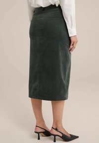 Zelena kordna midi suknja ravnog kroja s dvije stražnje džepove. Uparena s crnim sandalama na visoku petu.
